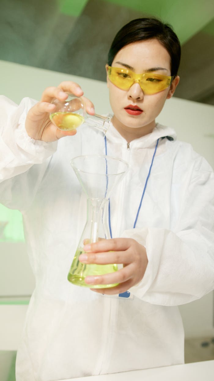 Female scientist in lab coat conducting an experiment with glassware.