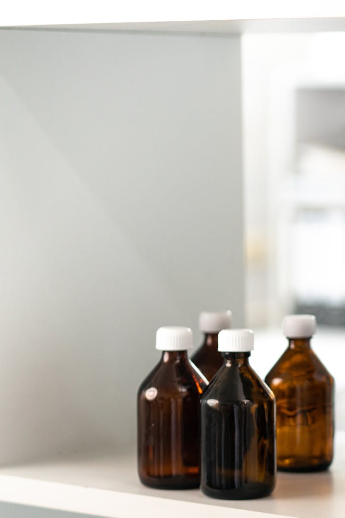 Four brown glass bottles with white caps on a shelf, ideal for storage or medical concepts.